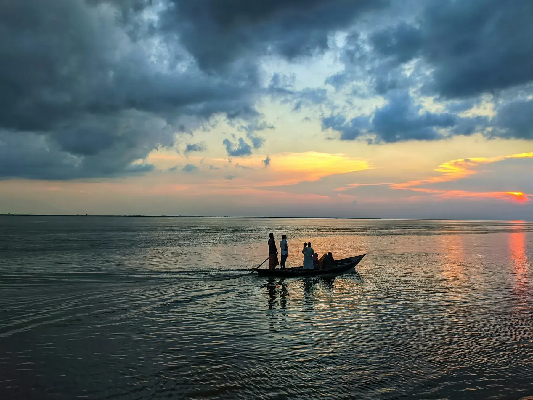 A small boat crossing the Padma at sunset