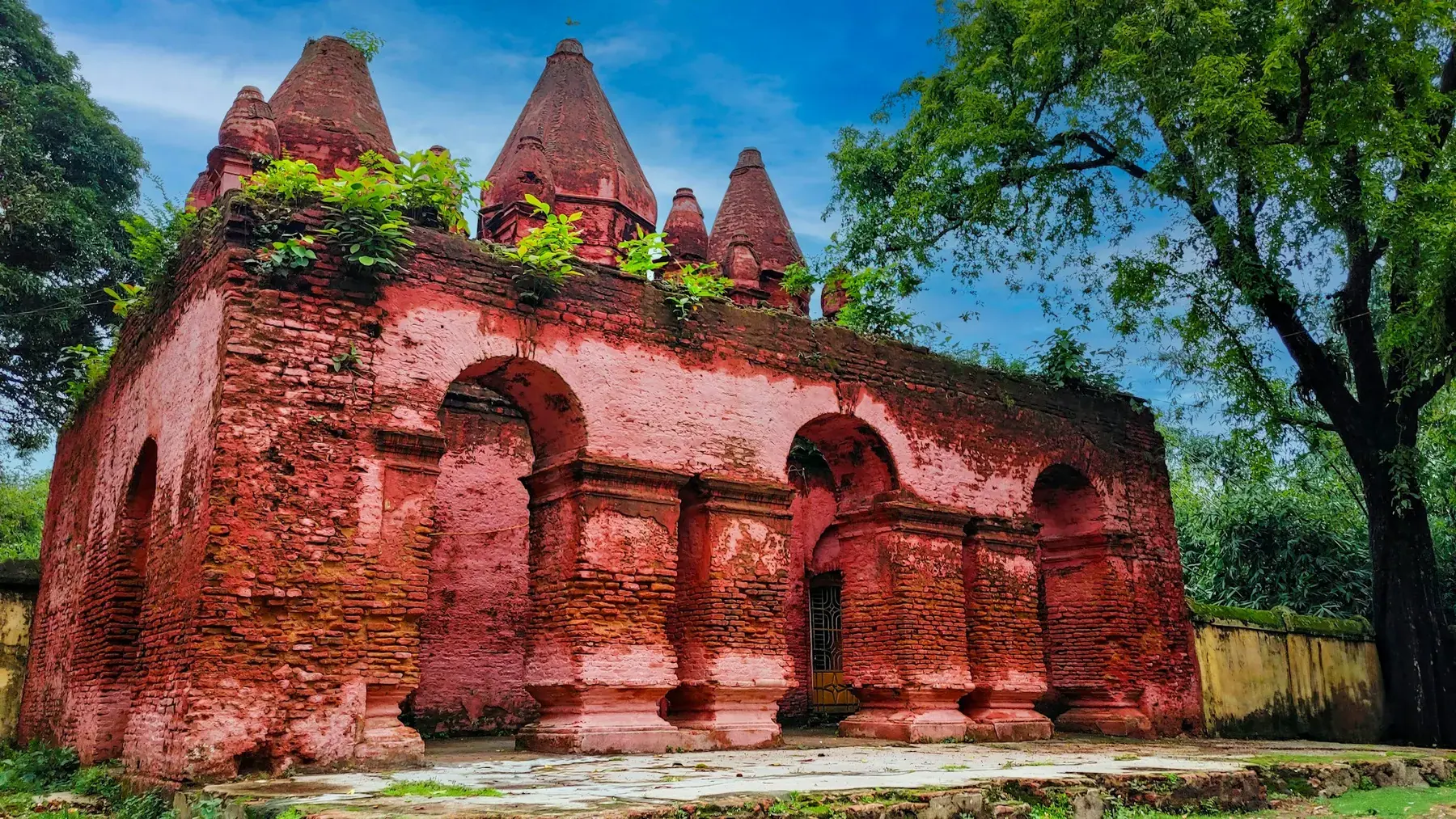 A historic brick temple surrounded by trees in Bangladesh