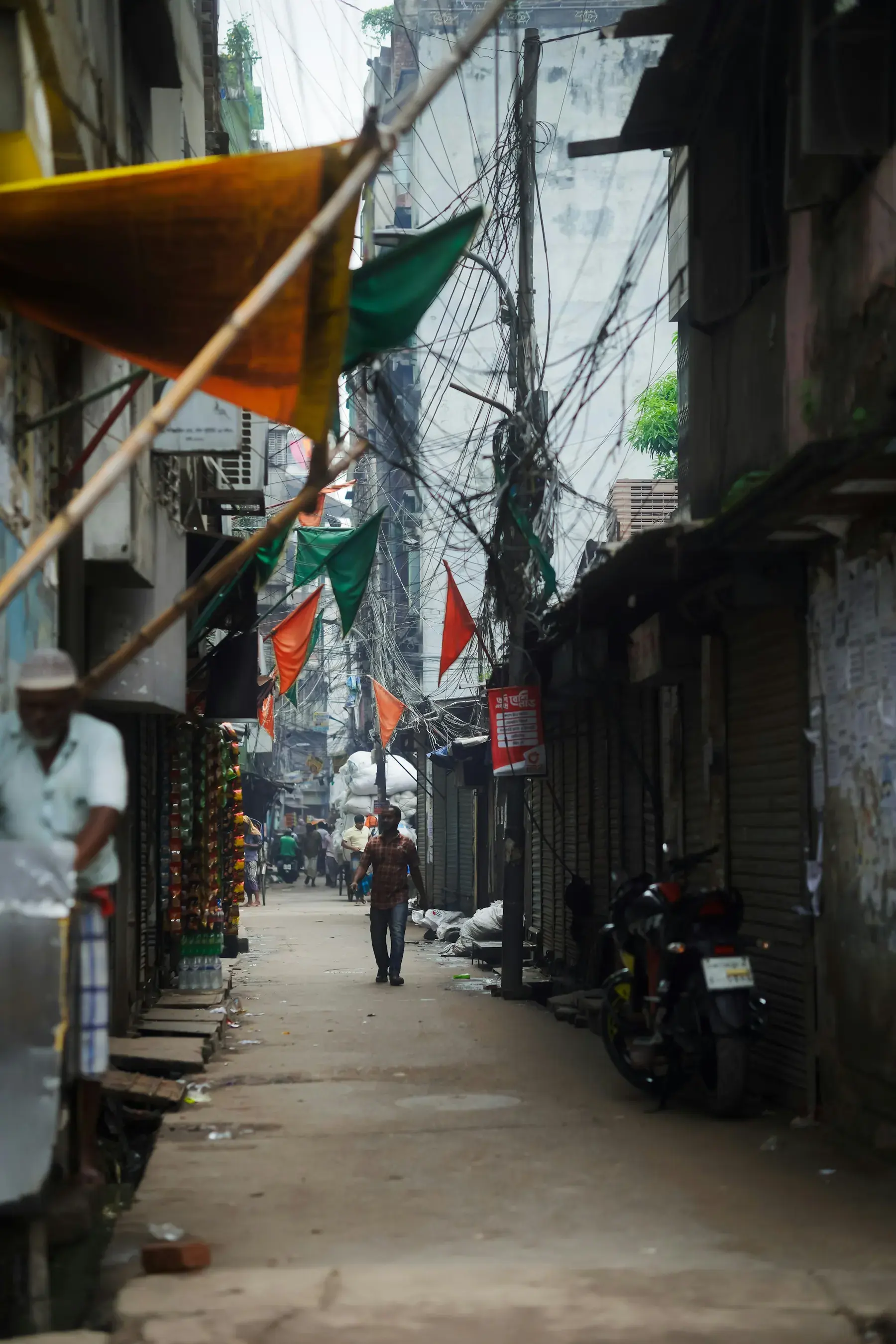 Pedestrians moving through a narrow Old Dhaka market lane