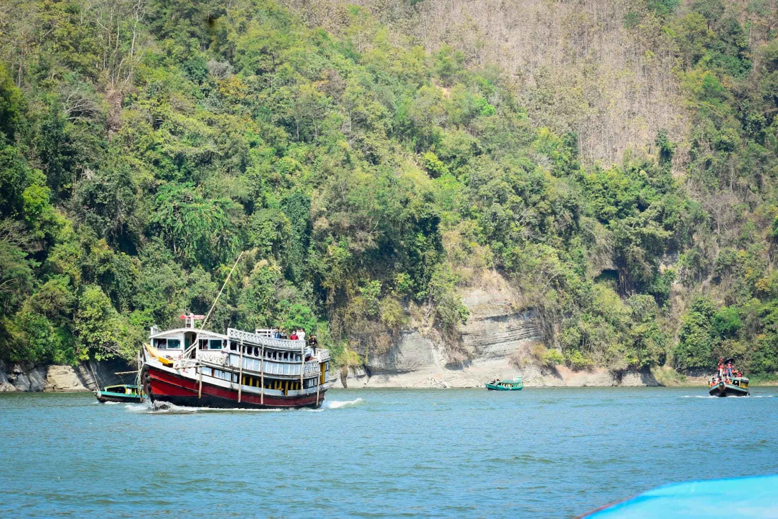 Boat crossing Kaptai Lake beside green hills in Rangamati, regional travel context for Chattogram Commonwealth War Cemetery